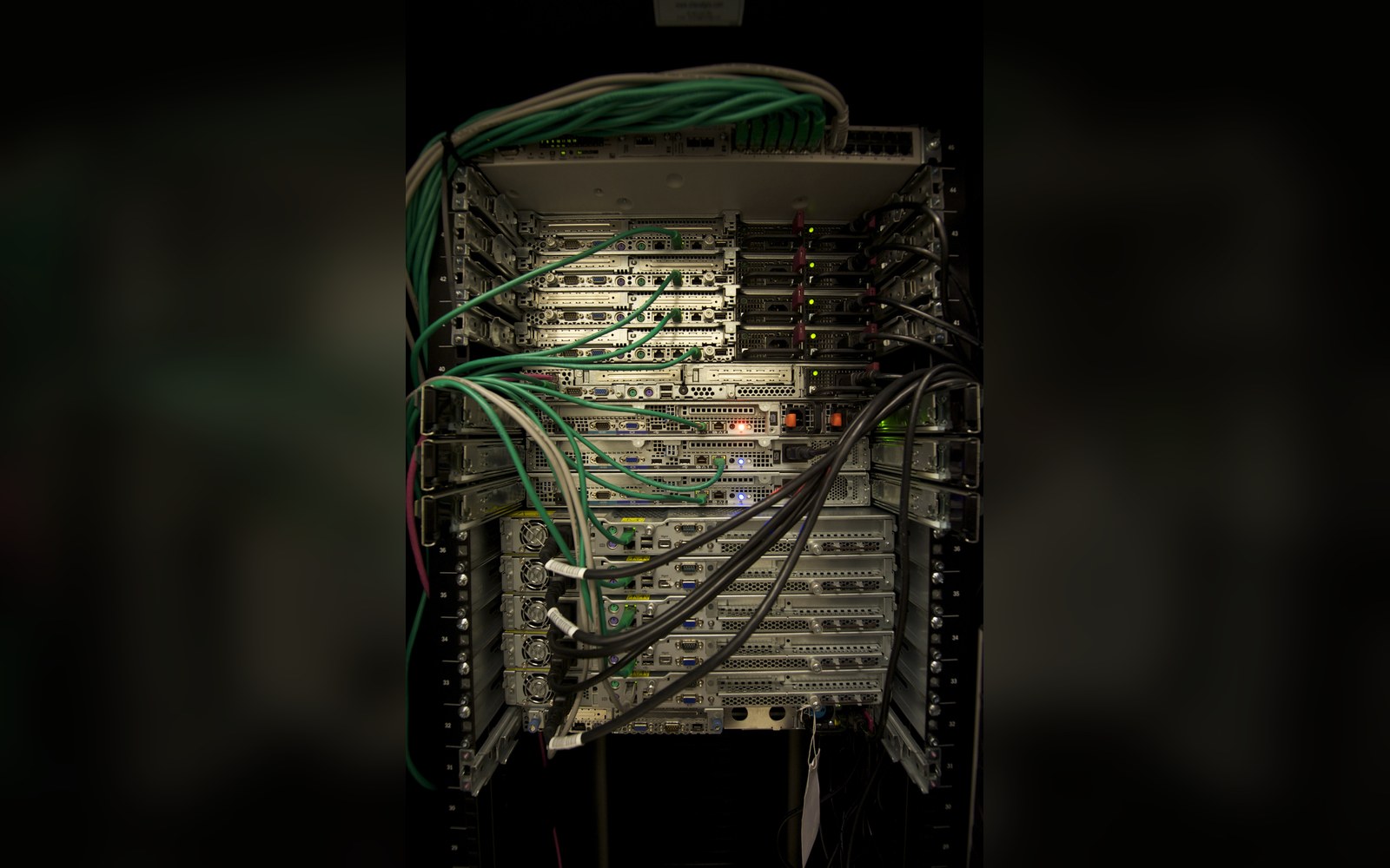 A rack of network gear behind a glass door with status lights